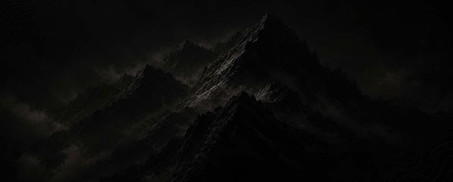 A dramatic monochrome mountain range shrouded in low light